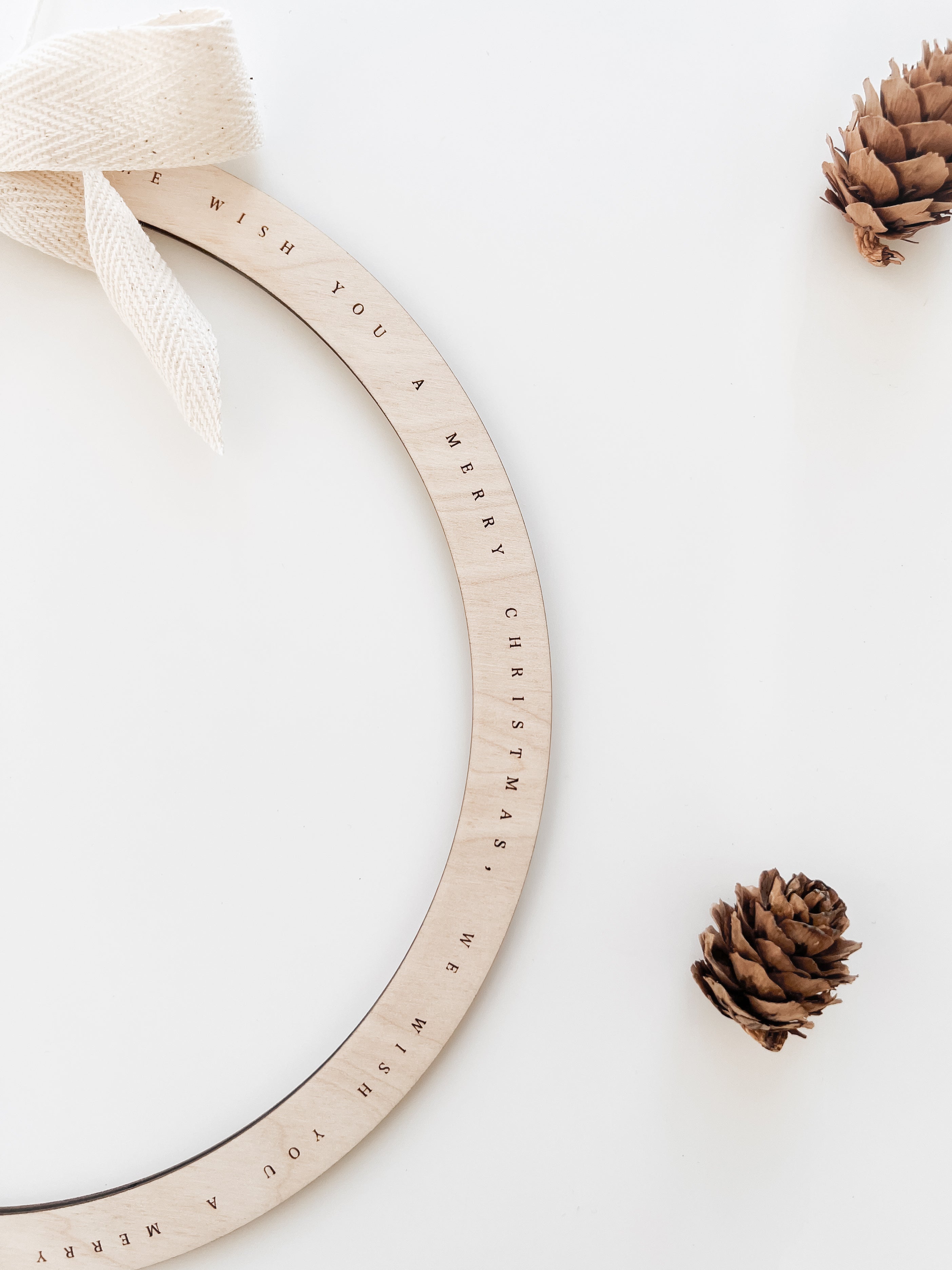 Nahaufnahme der Liedgravur „We Wish You a Merry Christmas“ auf dem hölzernen Weihnachts-Türkranz.