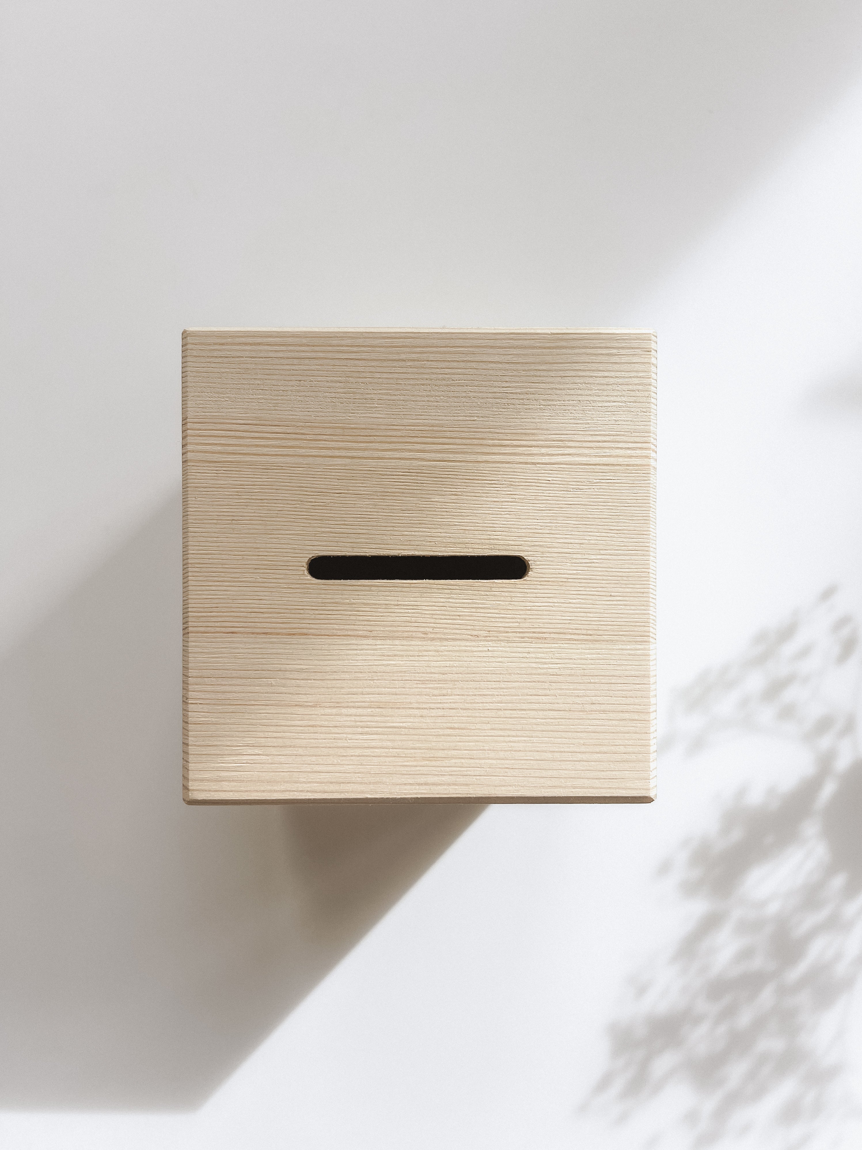 Detailaufnahme des Sparschlitzes einer Holzspardose mit zartem Motiv.